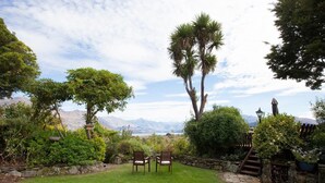 A well-maintained garden with a lawn, stone wall, and seating area. - Kauri House (Wanaka)