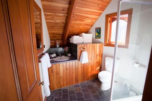 Un baño con paneles de madera, un lavabo, un inodoro y una zona de ducha.
