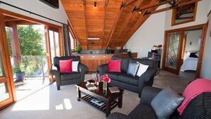 A modern living room with two sofas, a coffee table, and a kitchen in the background. - Kauri House (Wanaka)
