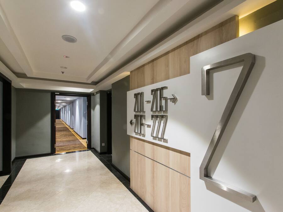 A modern hallway with a wooden panel wall, a large number '7' sign, and a corridor leading to a room with a wooden floor.