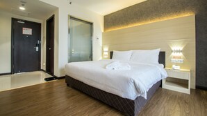 A hotel room with a large bed, bedside tables, a nightstand, a window with blinds, and a door. - Hotel Labuan Point (Labuan)