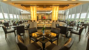 A modern restaurant with a central bar, multiple tables, and chairs arranged for dining. - Hotel Labuan Point (Labuan)