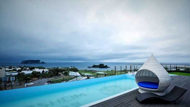 A modern pool area with a unique conical chair, a clear view of the sea, and distant islands.