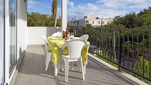 A balcony with a table and chairs, a view of the neighborhood, and a palm tree. - Villa Alexis Self-Catering (Trou aux Biches)