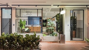 Un hall d’hôtel moderne avec un comptoir d’accueil, des plantes d’intérieur et une grille en métal.