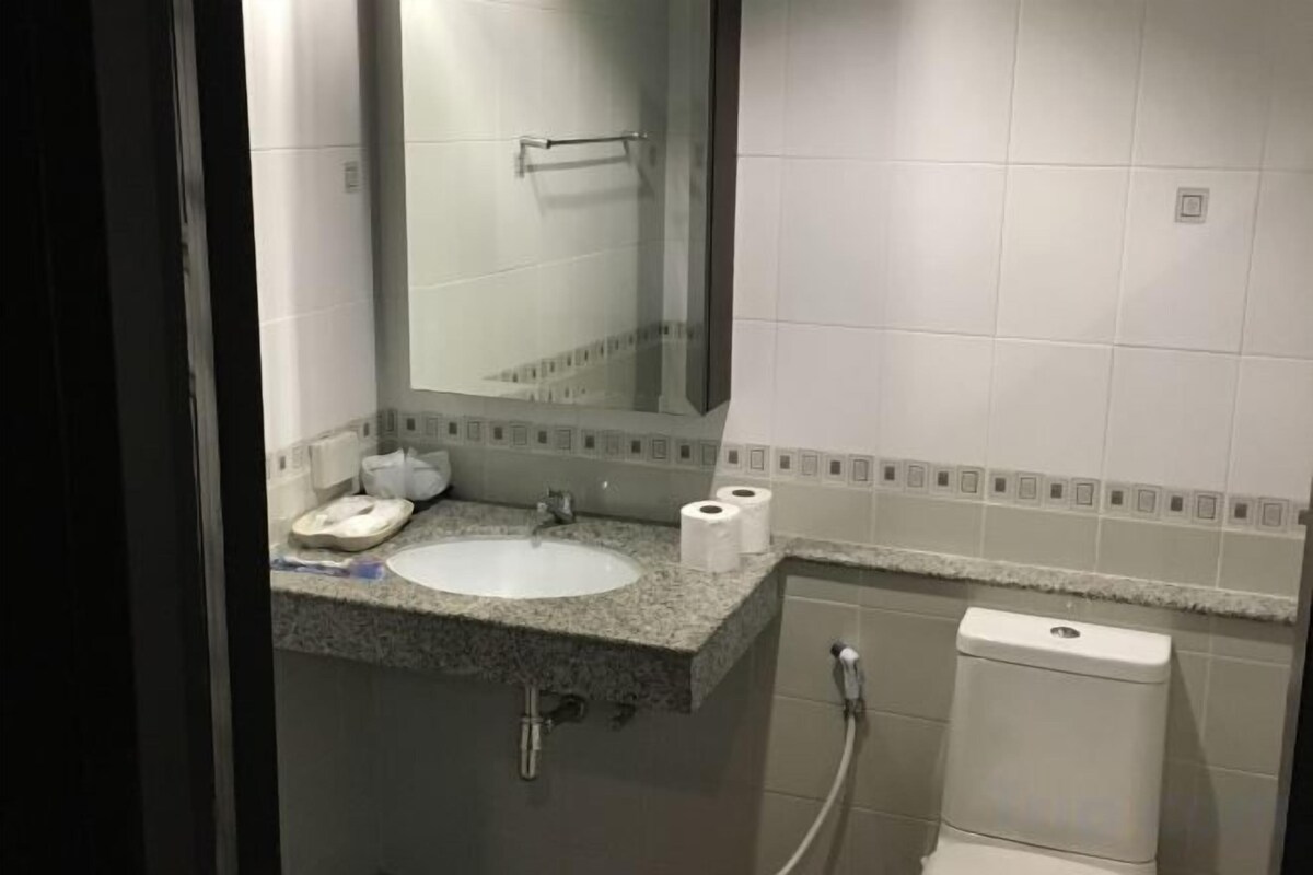 Uma casa de banho com lavatório, espelho, sanita e chuveiro.