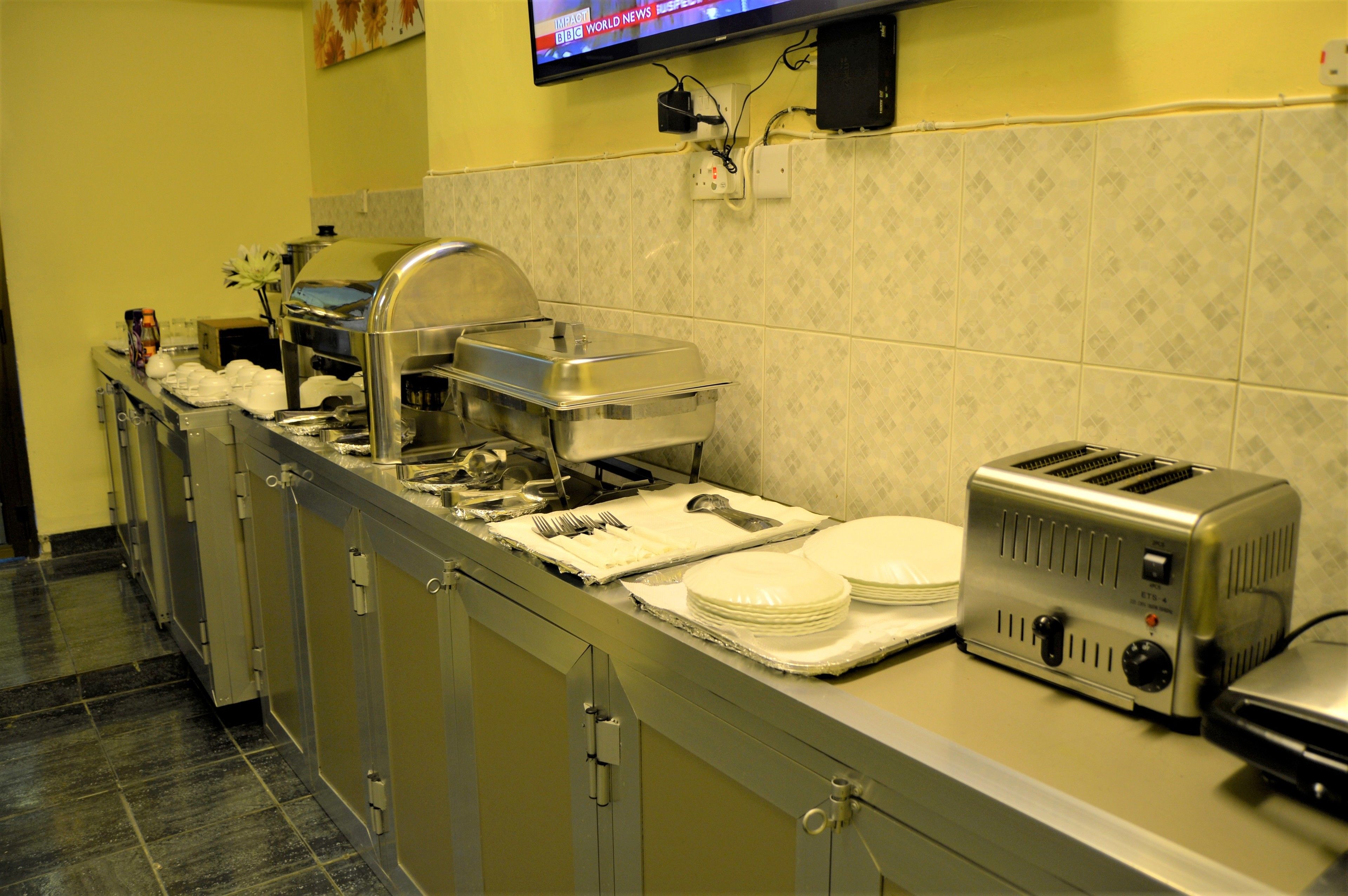 A buffet setup with a toaster, plates, and utensils.