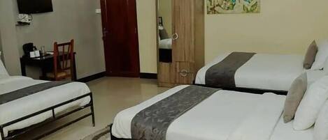A hotel room with two beds, a desk, a chair, a wardrobe, and a TV on the wall.