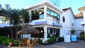 A bar and restaurant with outdoor seating, a thatched umbrella, and a signboard. - M Hotel Mbezi (Dar es Salaam)