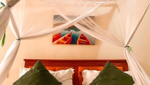 A bed with white linens and green pillows, a wooden headboard, and a painting above it. - M Hotel Mbezi (Dar es Salaam)