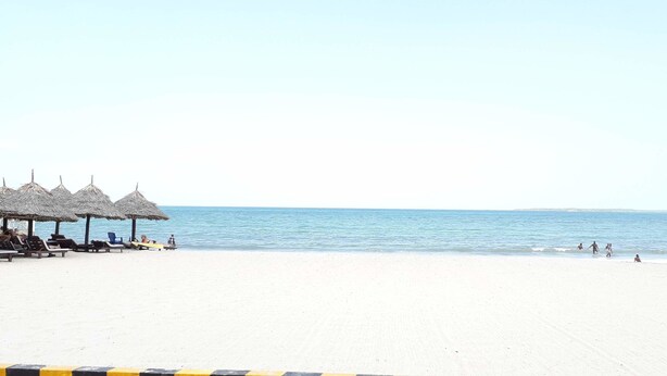 A beach with thatched umbrellas and lounge chairs. - M Hotel Mbezi (Dar es Salaam)