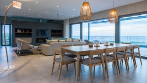 A modern living room with a large dining table, sofas, and a TV. - Romans Villa (Gansbaai)