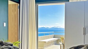 A hotel room with a bed, a view of the sea, and a balcony. - Romans Villa (Gansbaai)