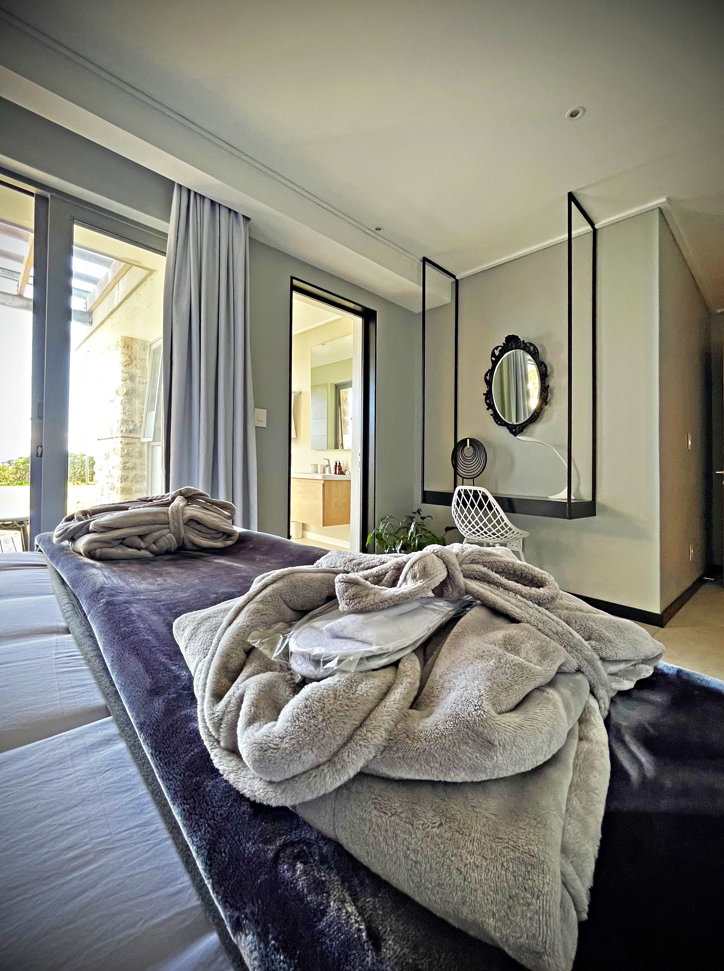 Ein modernes Schlafzimmer mit einem großen Bett, einem durchgegangenen Tür sichtbaren Badezimmer und Blick ins Freie.