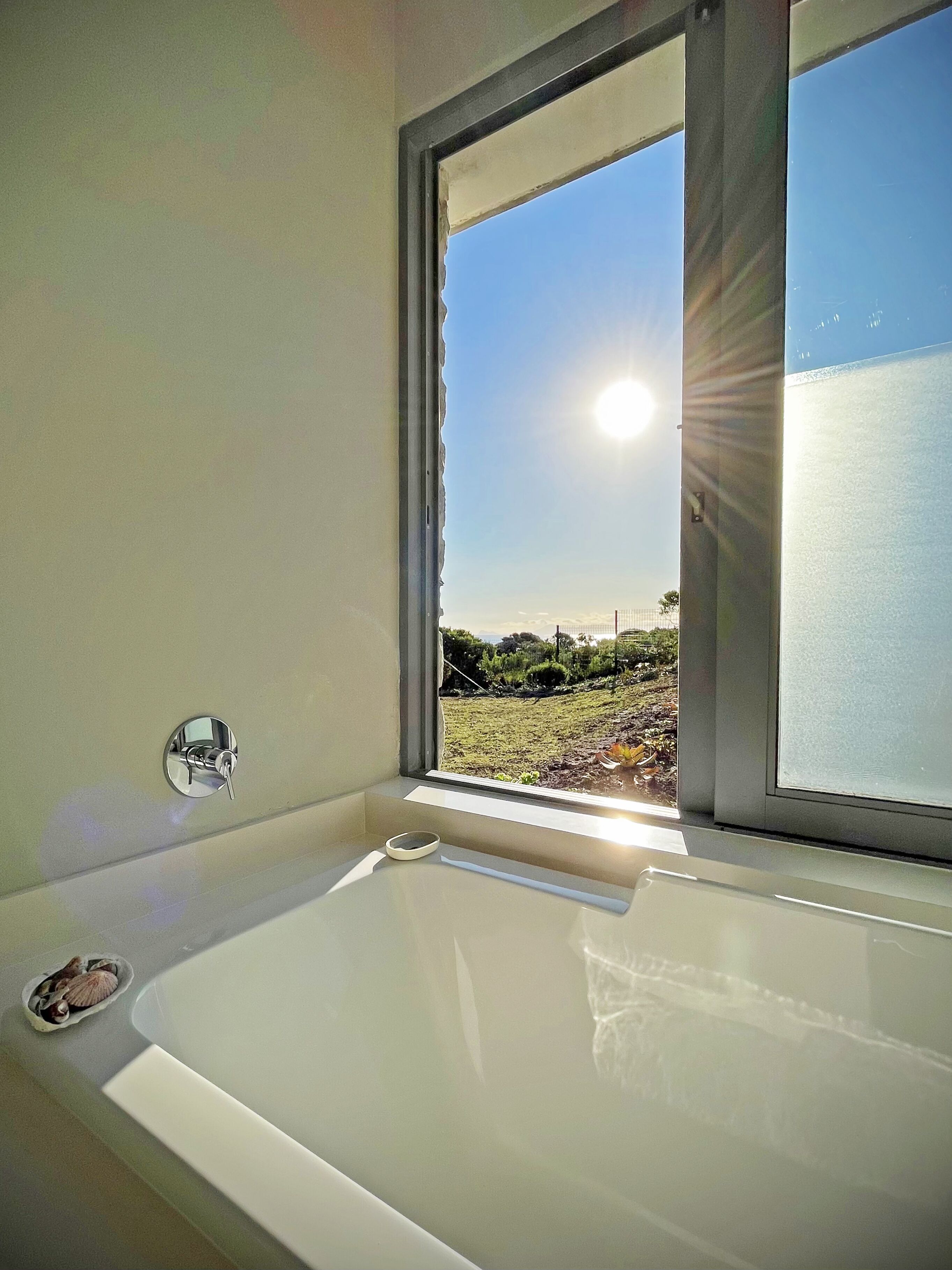 A bathroom with a bathtub, a window, and a view of a landscape.