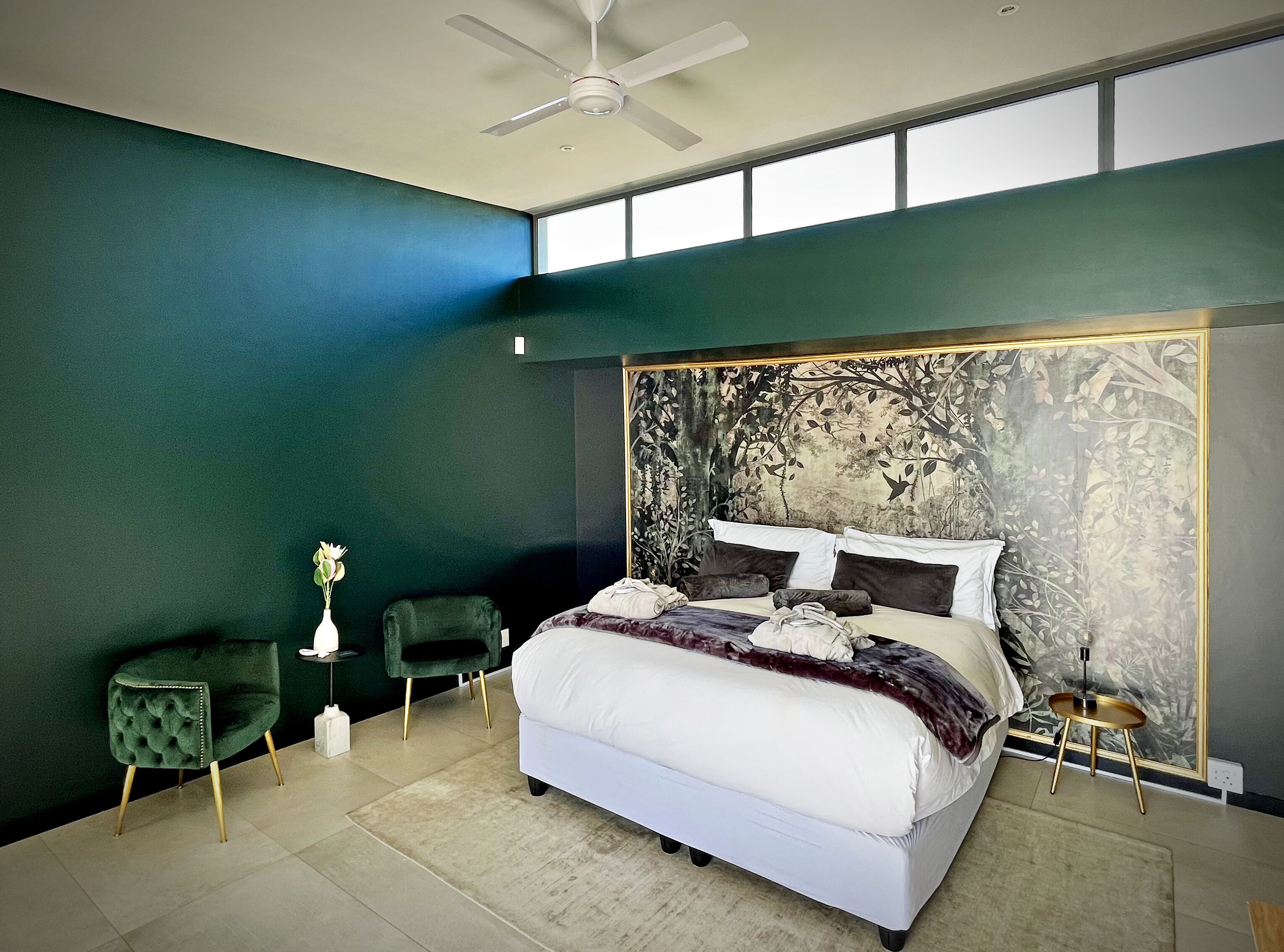 Un dormitorio moderno con una cama grande, un ventilador de techo y vistas por la ventana.