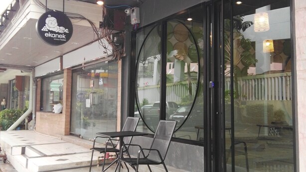 Ein Café mit Außenbereich, einer Schautafel und einer Treppe zu einer oberen Etage.