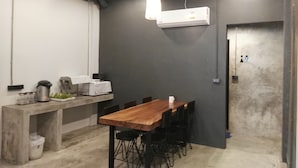 Ein modernes Zimmer im Industrial-Stil mit einem Betontisch und -stühlen, einer Klimaanlage und einer Deckenleuchte.
