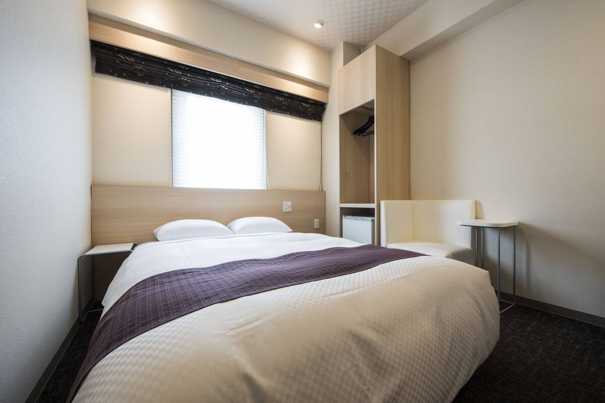 Une chambre d’hôtel avec un grand lit, une table de chevet, un miroir et une armoire.