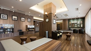 A modern lobby with wooden flooring, a reception desk, seating areas, and framed pictures on the walls. - Nagasaki Bus Terminal Hotel (Nagasaki)
