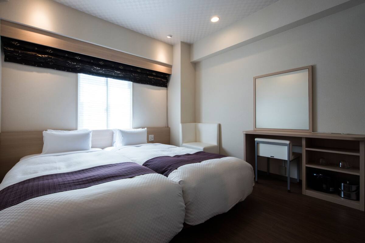 Une chambre d’hôtel moderne avec un grand lit, des tables de chevet, un miroir et un téléviseur intégré.