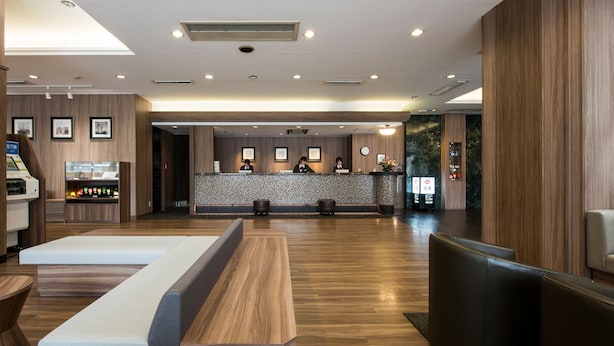 A modern hotel lobby with a reception desk, seating area, and a reception counter. - Nagasaki Bus Terminal Hotel (Nagasaki)