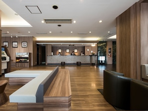 Un moderno vestíbulo de hotel con un mostrador de recepción, una zona de estar y una recepción.