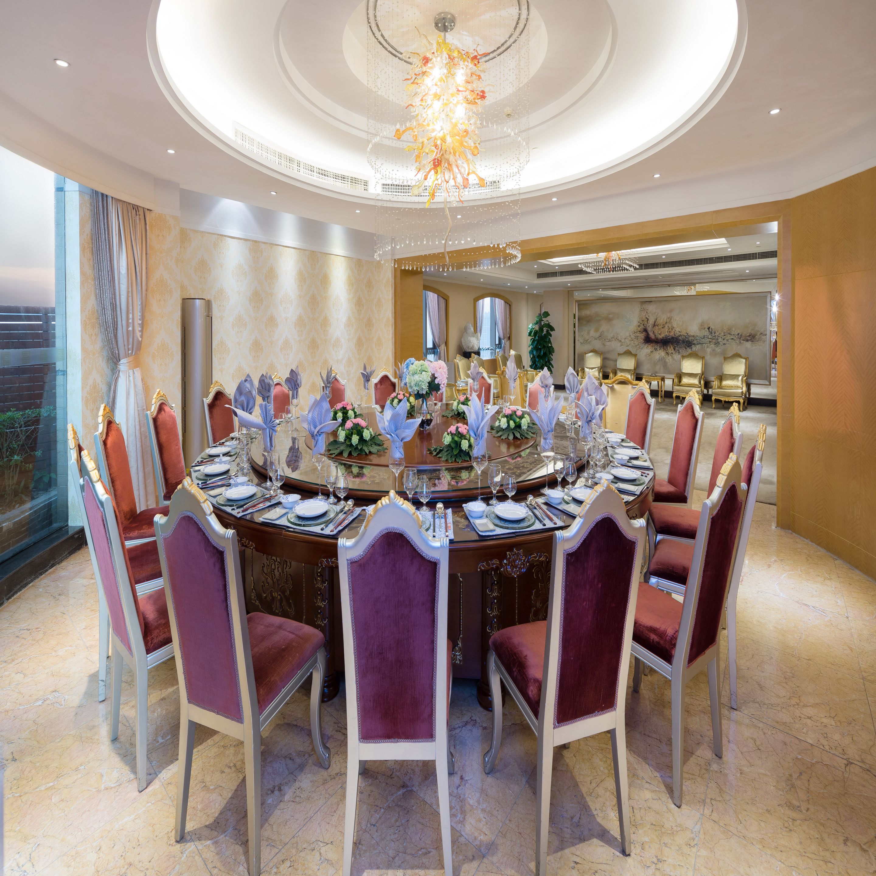 Une salle à manger élégante, avec une table ronde dressée pour le repas, entourée de chaises richement décorées.