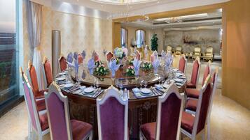 Une salle à manger élégante, avec une table ronde dressée pour le repas, entourée de chaises richement décorées.