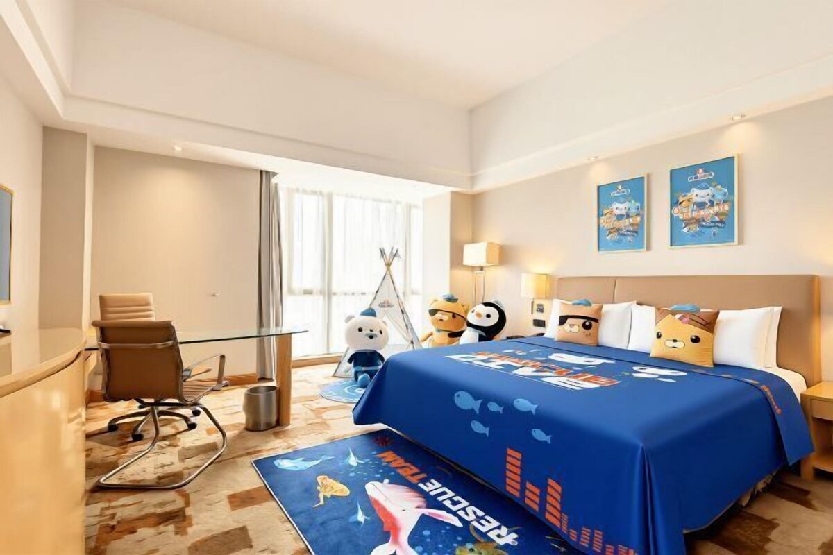 Ein Hotelzimmer mit Bett, Schreibtisch, Stuhl, Fenster und einer Wand mit zwei gerahmten Bildern.