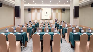 A conference room with multiple tables, chairs, and a presentation screen.