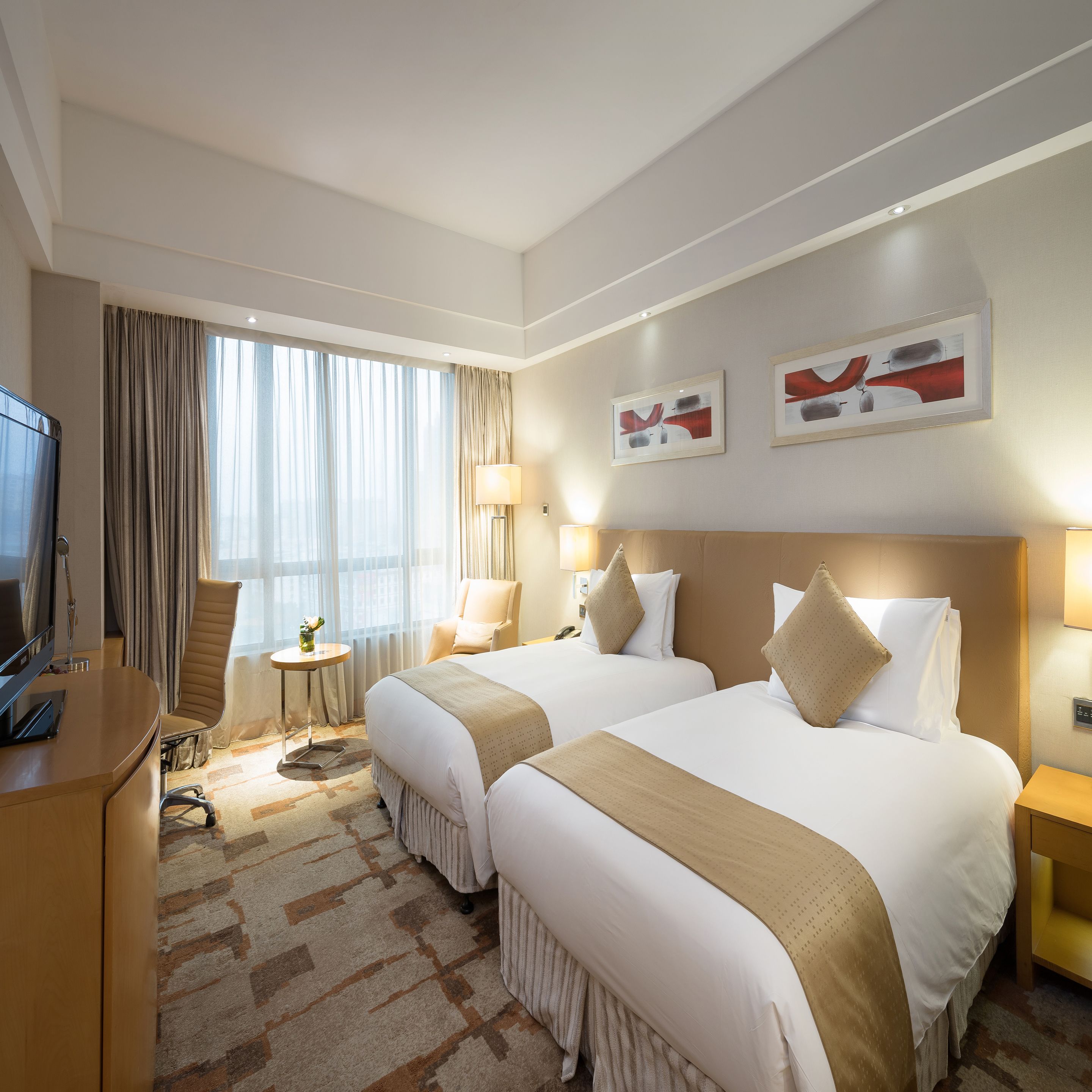 Habitación de hotel con dos camas, un escritorio, un televisor y una ventana con cortinas.