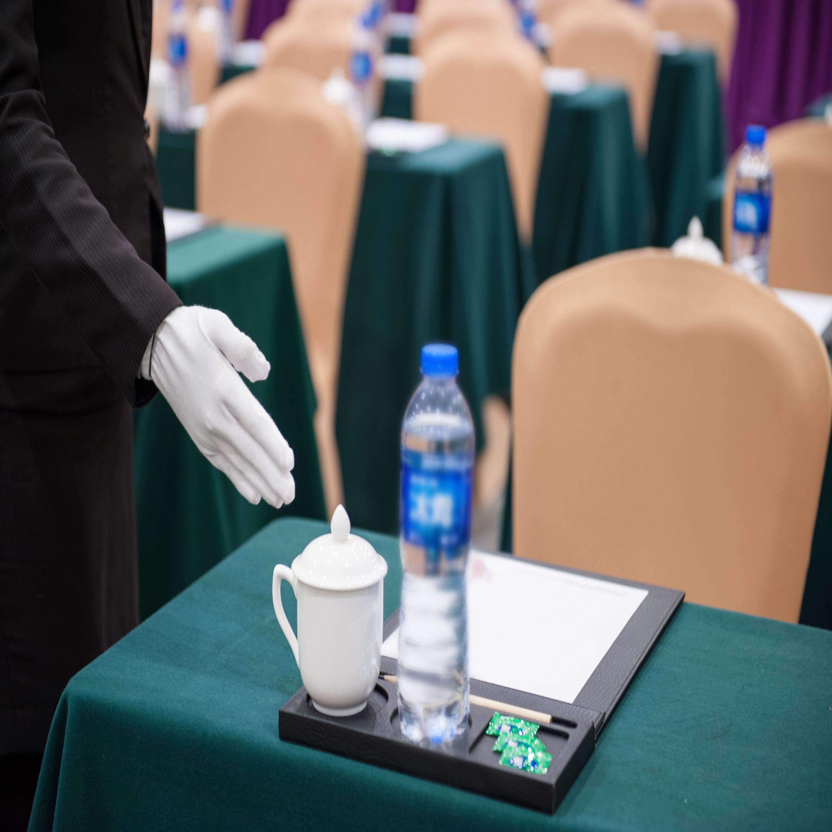 A conference table with a white mug, a water bottle, and a small electronic device.