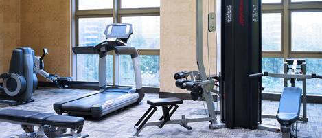 A gym with treadmills, dumbbells, and weight machines.