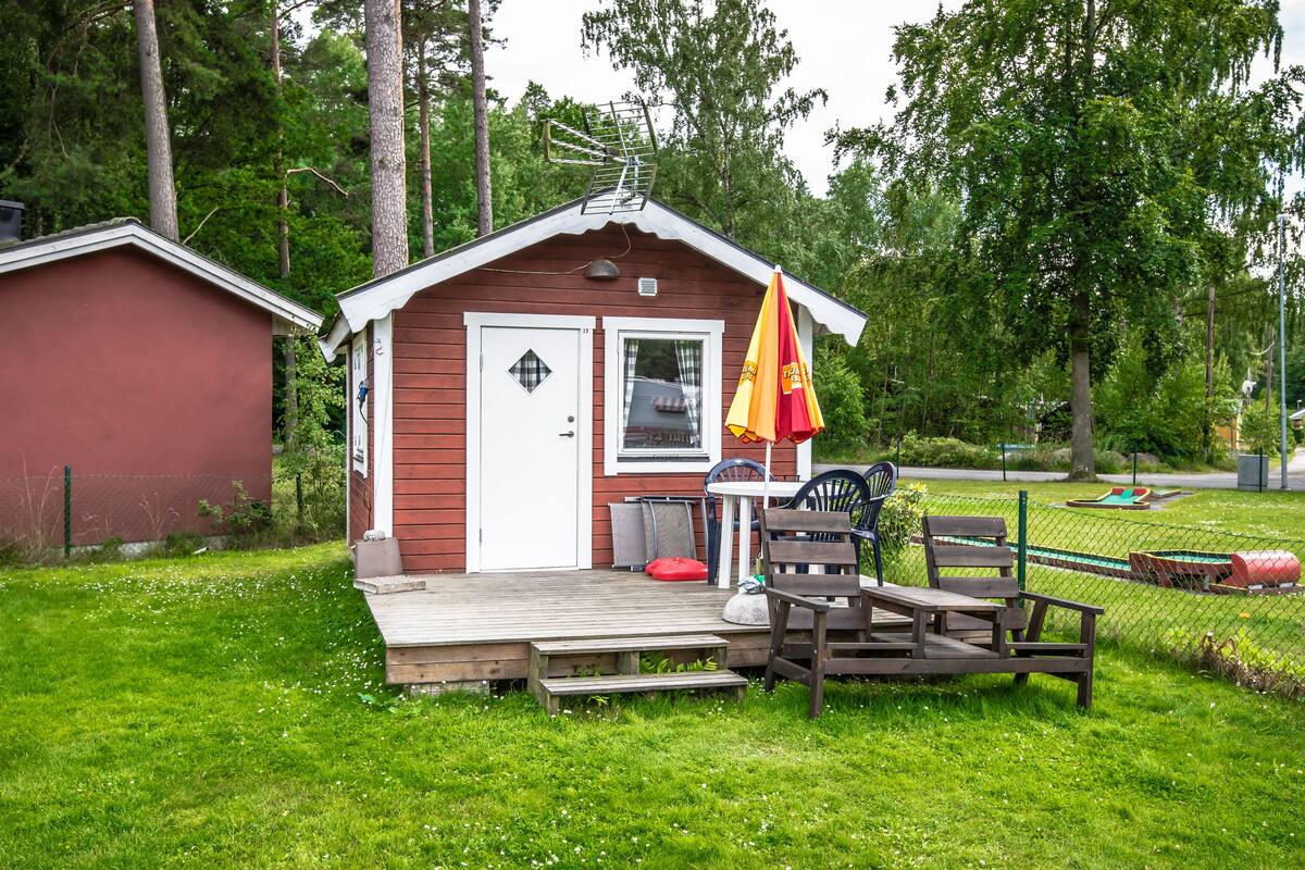 En hyggelig træhytte med veranda, flag og bænk.