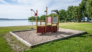 A playground with a swing set and climbing structures near a lake.