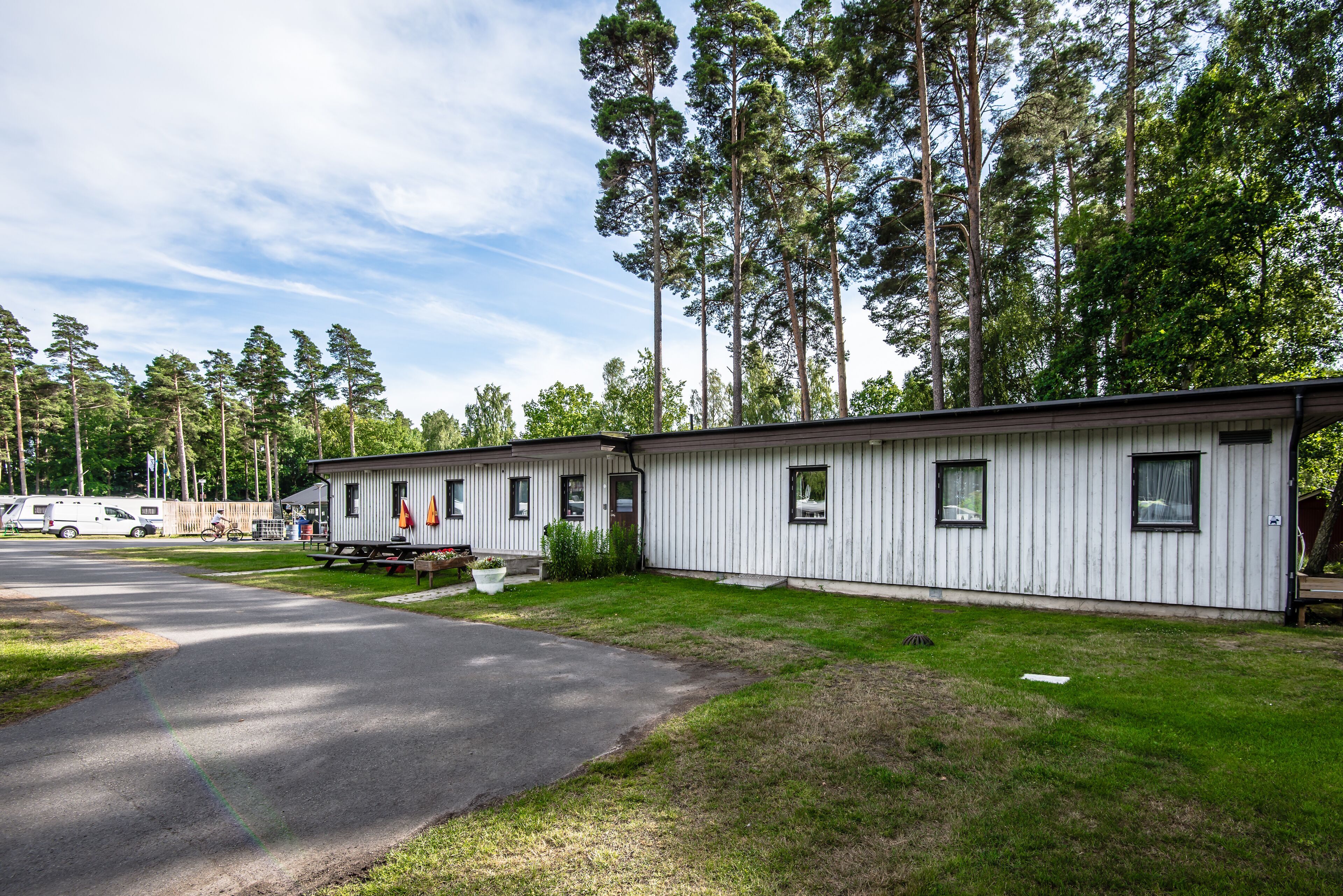 A row of single-story mobile homes with a paved driveway and a grassy area in front.