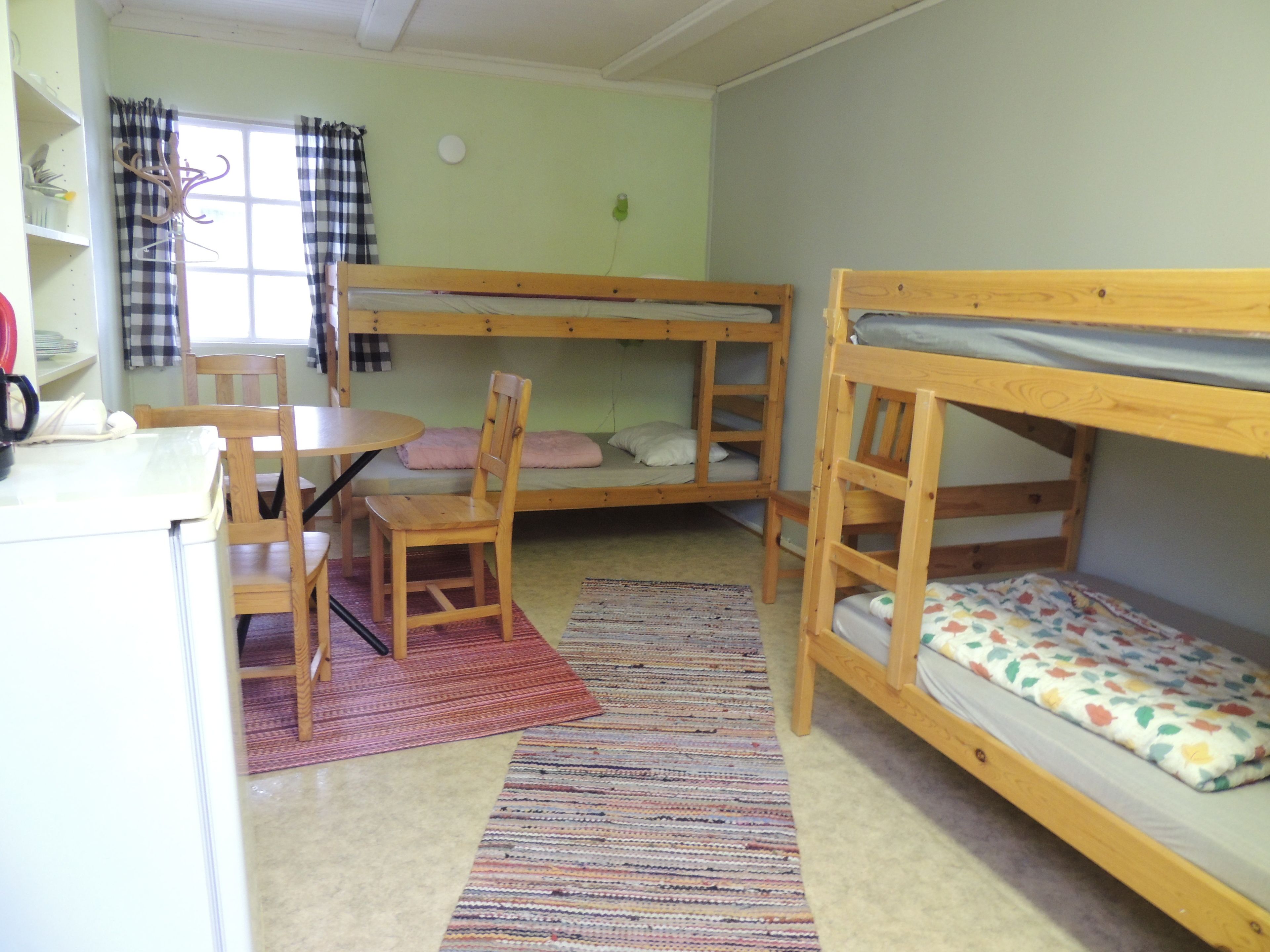 Una camera del dormitorio con letti a castello, una scrivania, una sedia e una finestra con tende.