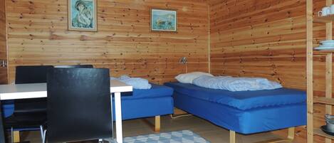 Eine Holzhütte mit zwei Betten, einem Tisch und Stühlen.
