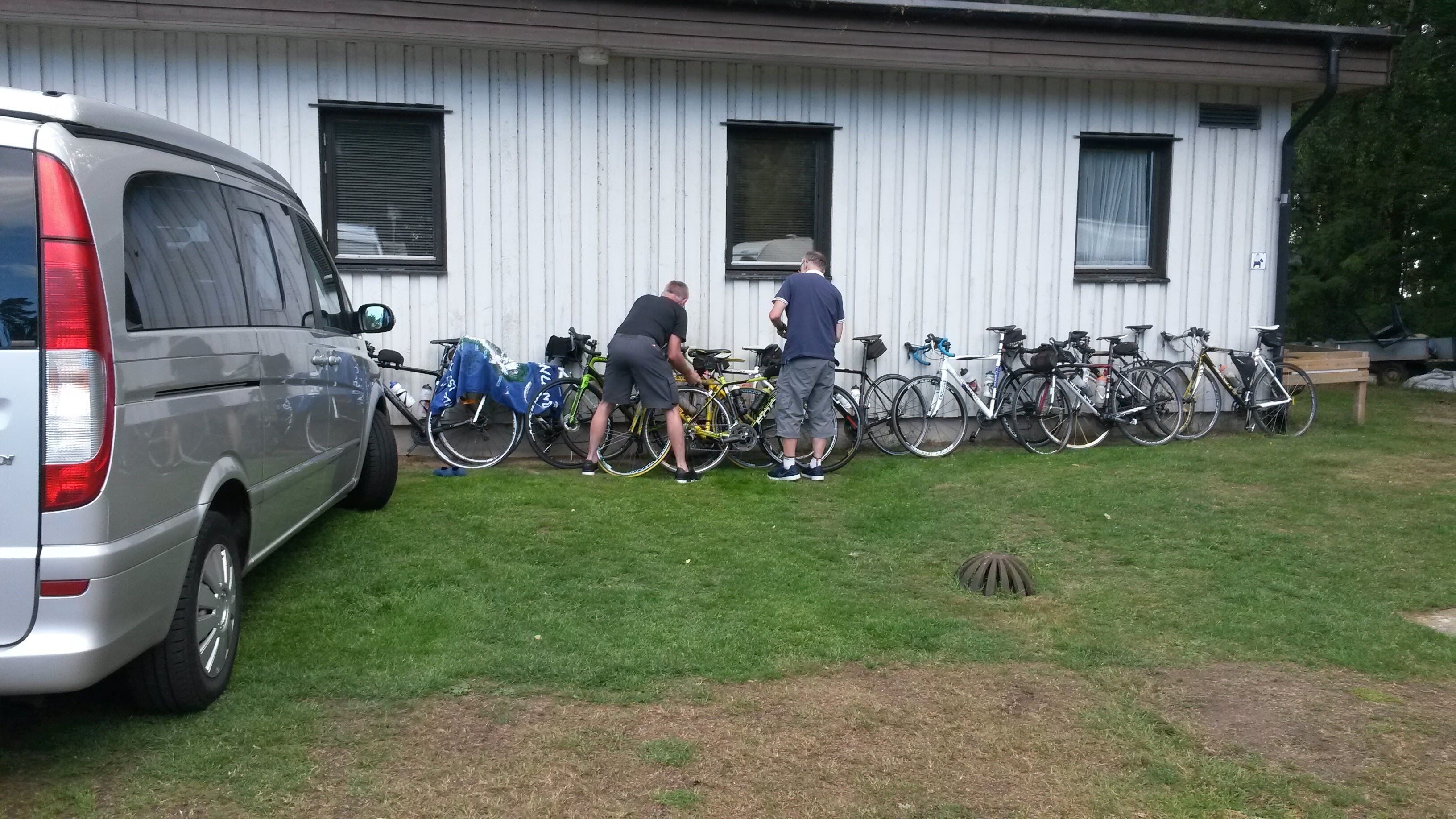 A building with a white exterior, a parked van, and multiple bicycles.