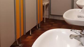 Baño con separadores amarillos y blancos, un lavabo blanco y piso de baldosas.