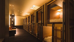 A row of bunk beds with wooden frames and a bench with orange cushions. - Yokkaichionsen Ofurocafe Yumoriza (Yokkaichi)