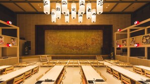 A spacious lecture hall with tiered seating, wooden tables, and a large screen at the front. - Yokkaichionsen Ofurocafe Yumoriza (Yokkaichi)