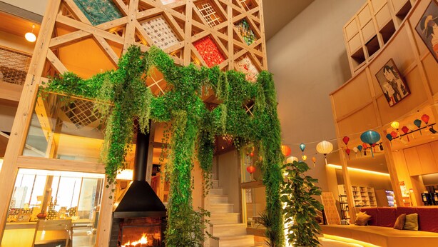 A modern interior with a fireplace, wooden staircase, and indoor plants. - Yokkaichionsen Ofurocafe Yumoriza (Yokkaichi)