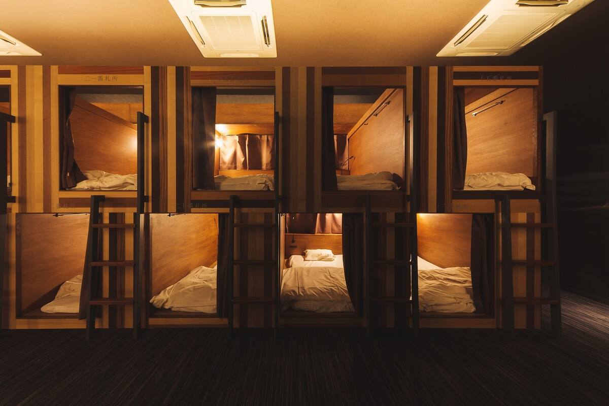 Une chambre de type dortoir, avec des lits superposés, des têtes de lit en bois et une allée centrale.