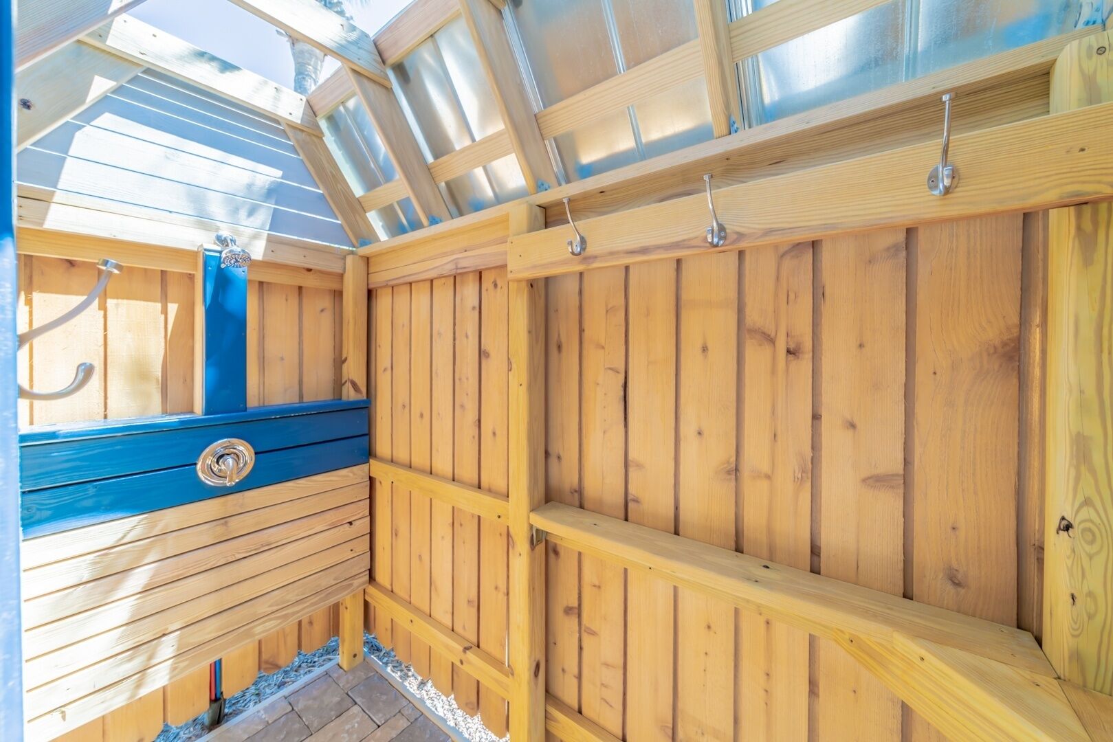 A wooden sauna with a skylight, a blue bench, and metal hooks on the ceiling.