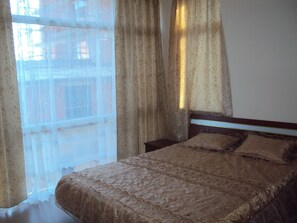 A bedroom with a bed, curtains, and a window.