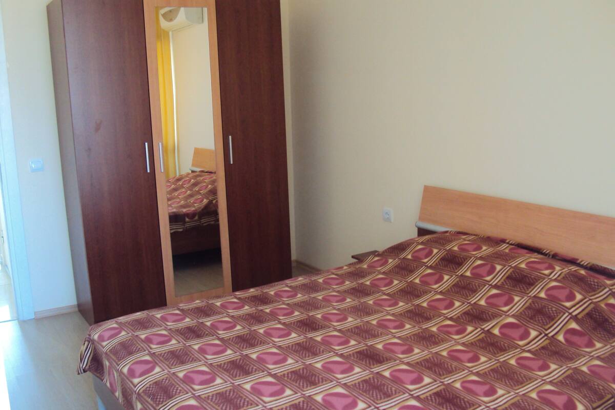 A bedroom with a bed, a wardrobe, and a mirror.