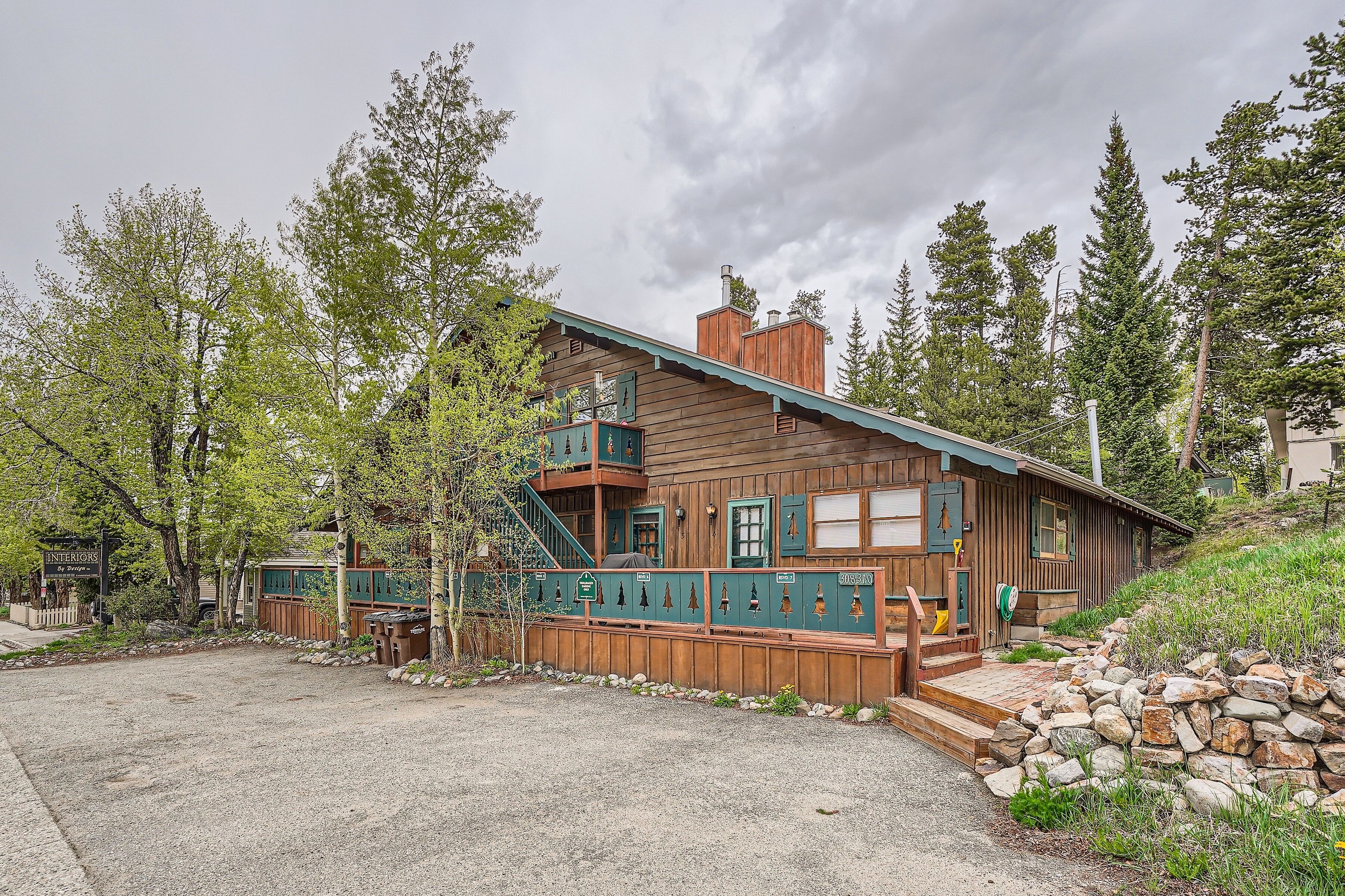 A rustic cabin with a wooden exterior, a stone staircase, and a view of surrounding trees.