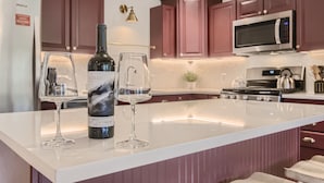 A kitchen with a white island, red cabinets, a refrigerator, a microwave, and a stove.